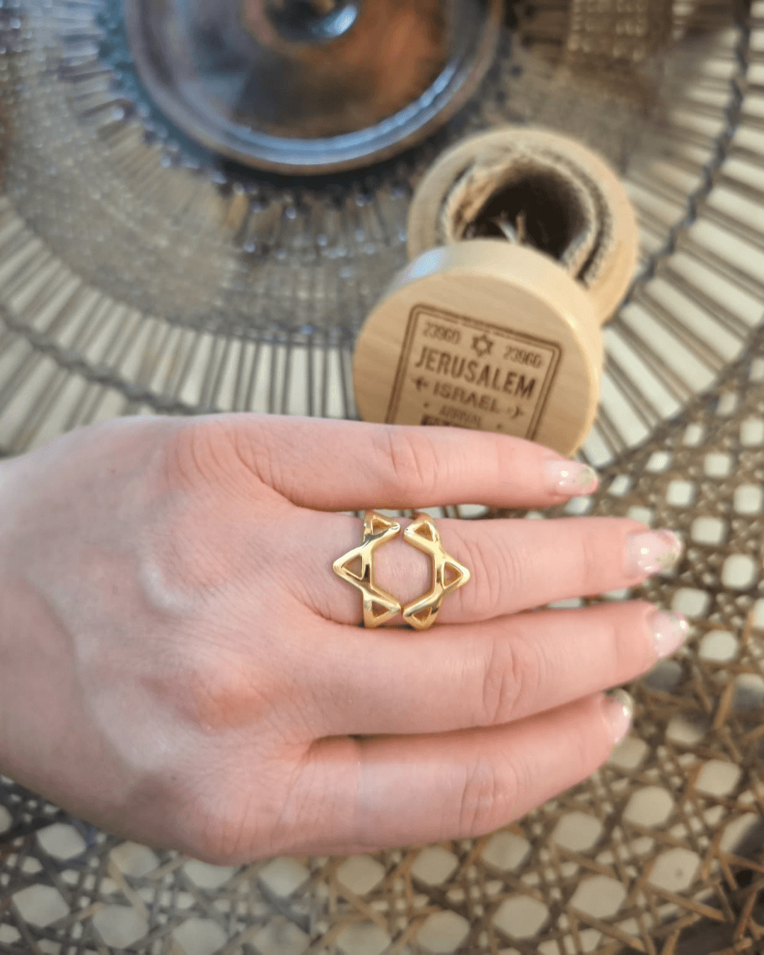 The gold vermeil ring worn on one finger, with the wooden keepsake box behind.