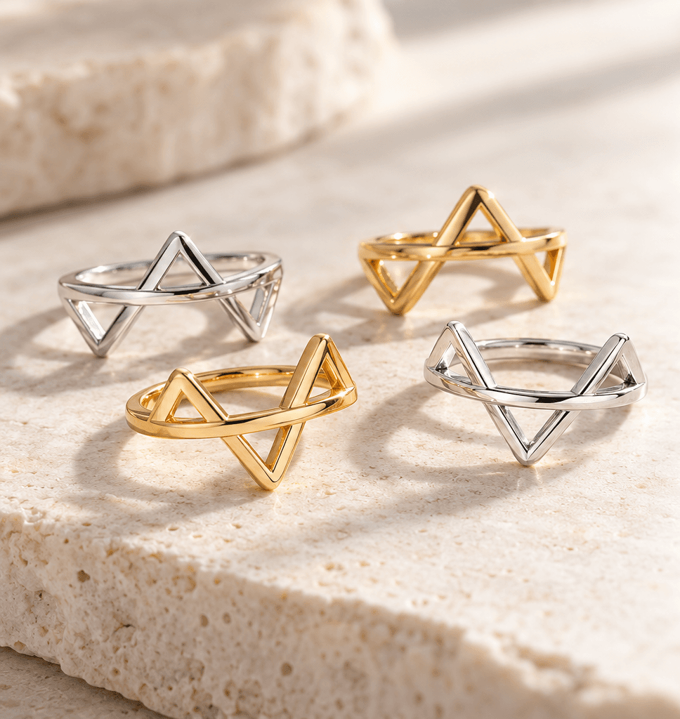 Ring pieces in sterling silver and 18K gold vermeil, each carrying one triangle, resting apart on pale stone.